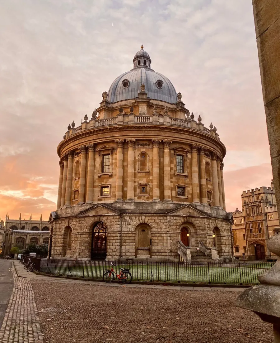 The Radcliffe Camera in Oxford at sunset, with a red bicycle by the railings